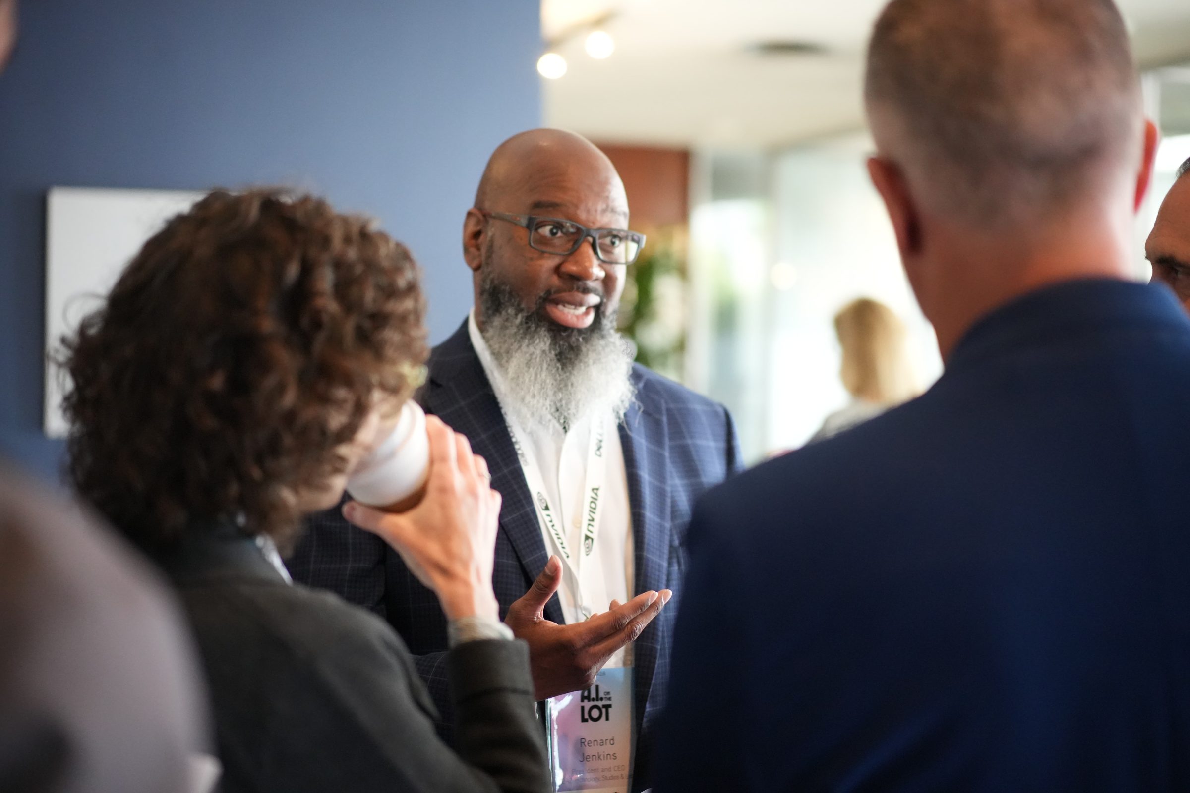Renard Jenkins, in a light suit and glasses, smiles while talking with attendees.