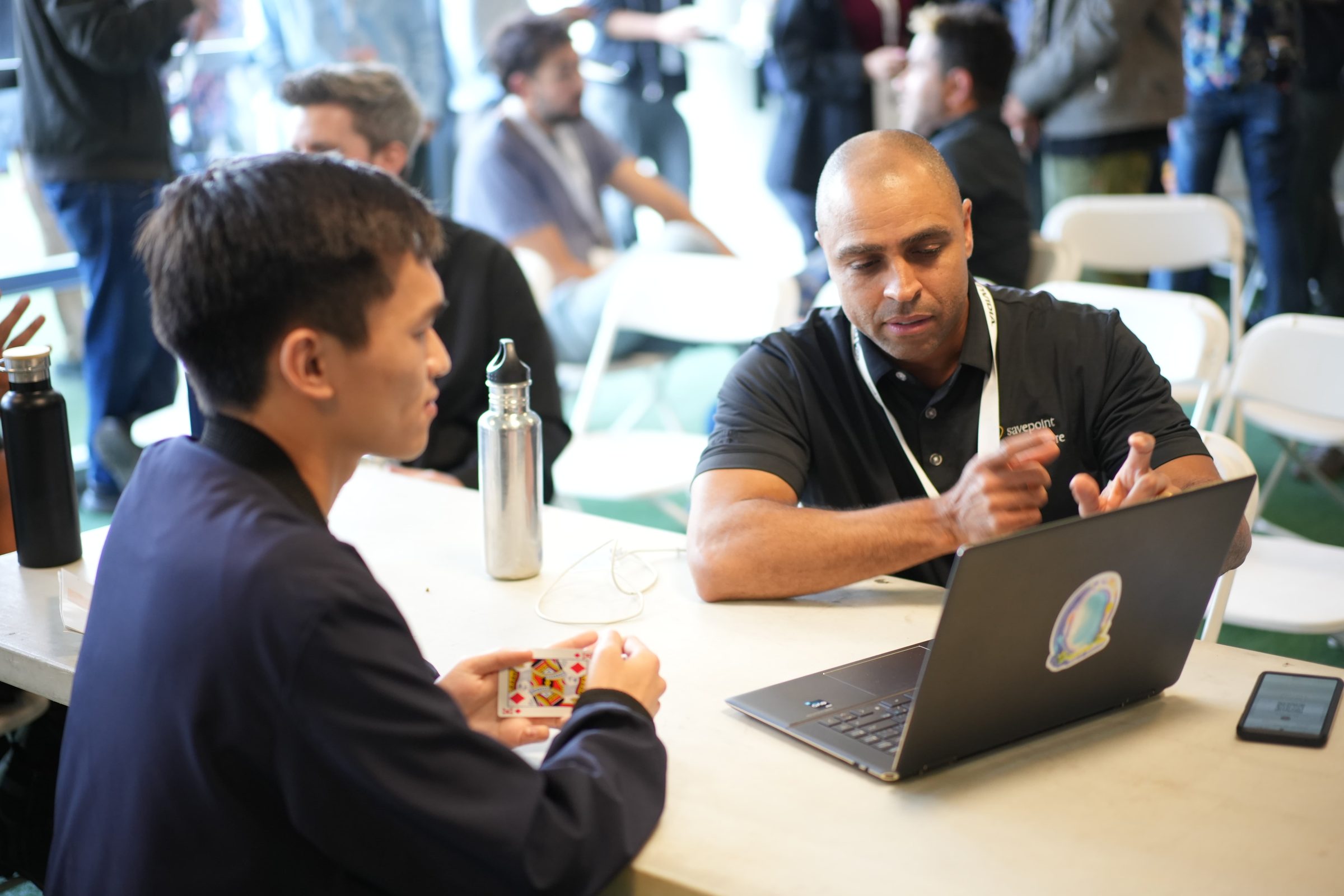 Two attendees sit across a laptop in the Gen Lab, one pointing at the screen.