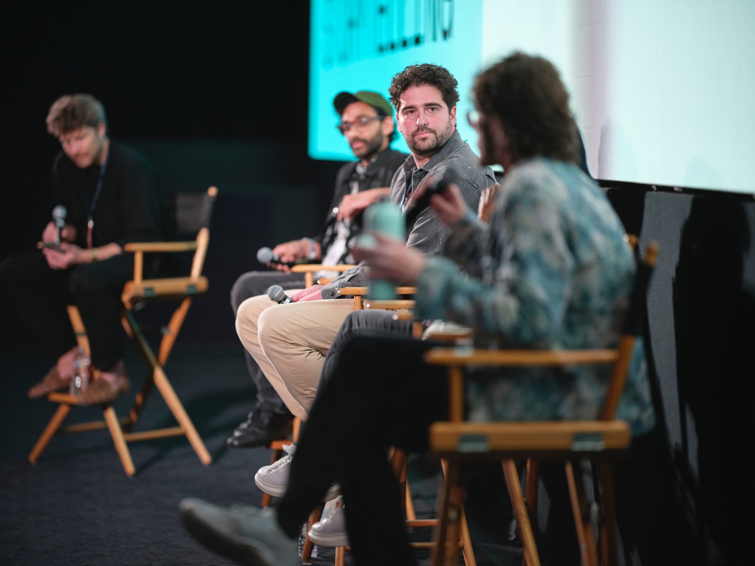 Four panelists in director's chairs, Andrew Ginzburg speaking into a microphone.