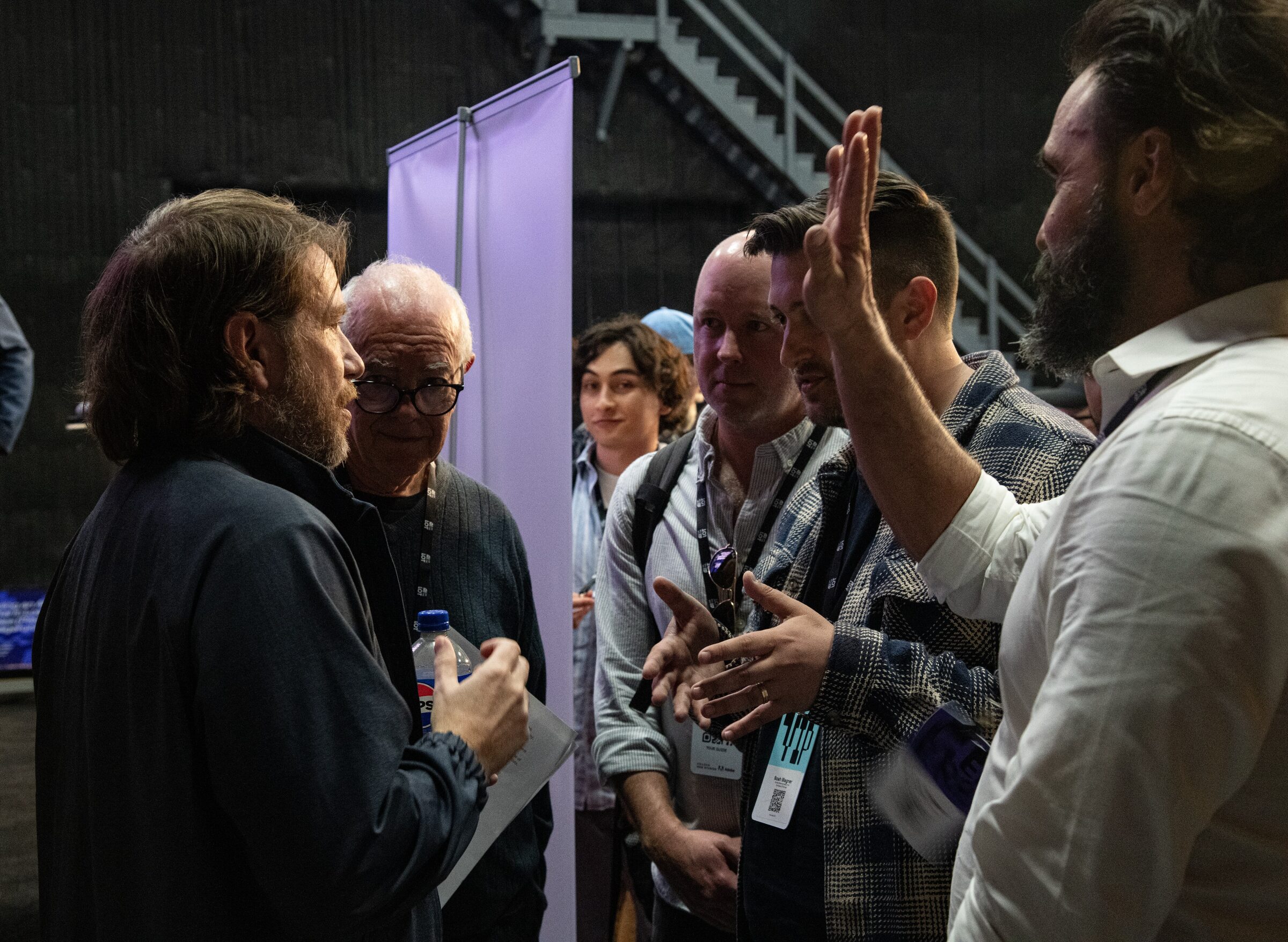 Gareth Edwards, notes in hand, listens as Noah Wagner raises a hand to make a point in a small huddle of filmmakers.