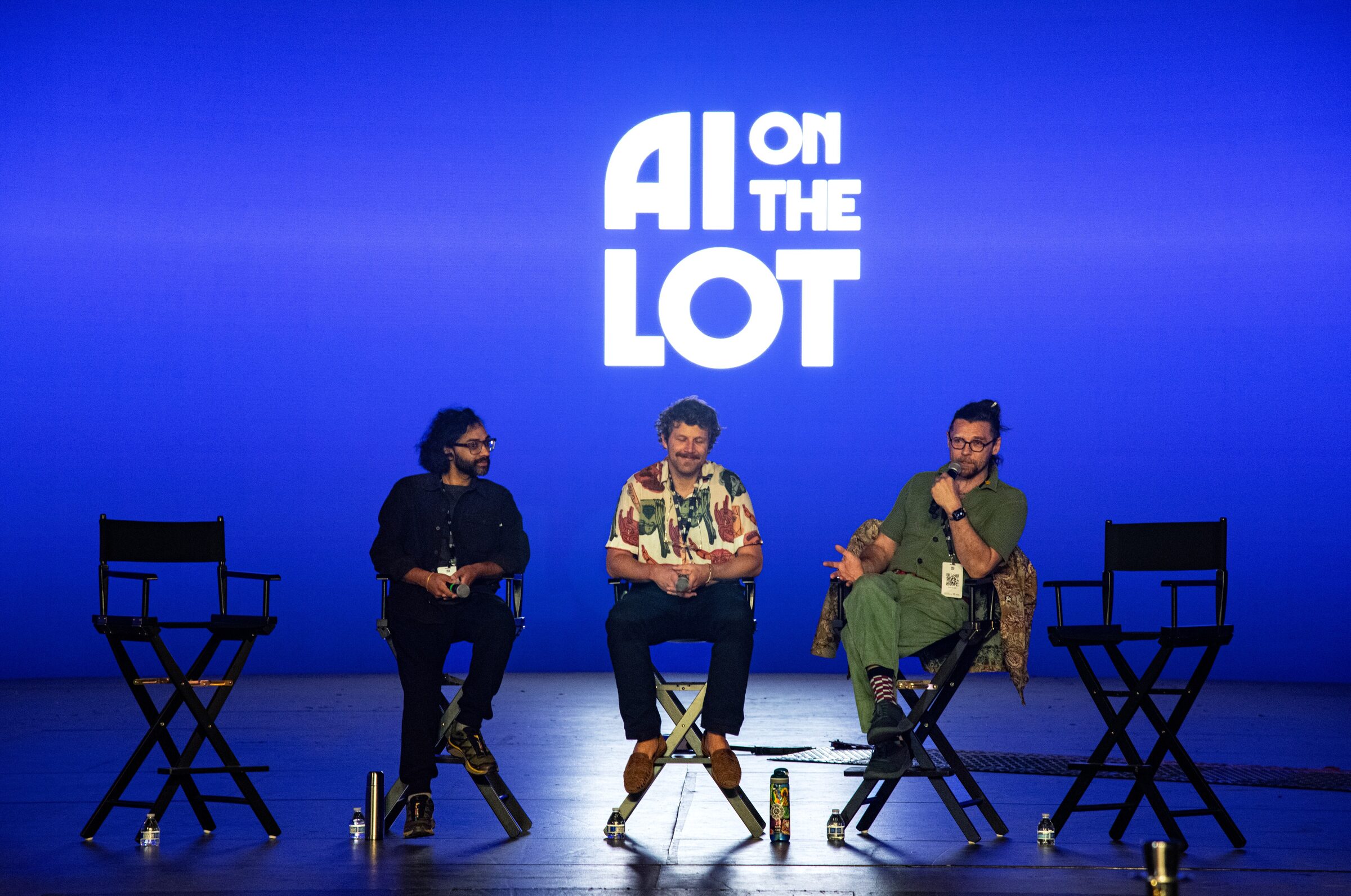 Parag Mital, Ian Eck and Oscar Sharp in director's chairs before a glowing blue AI on the Lot backdrop.