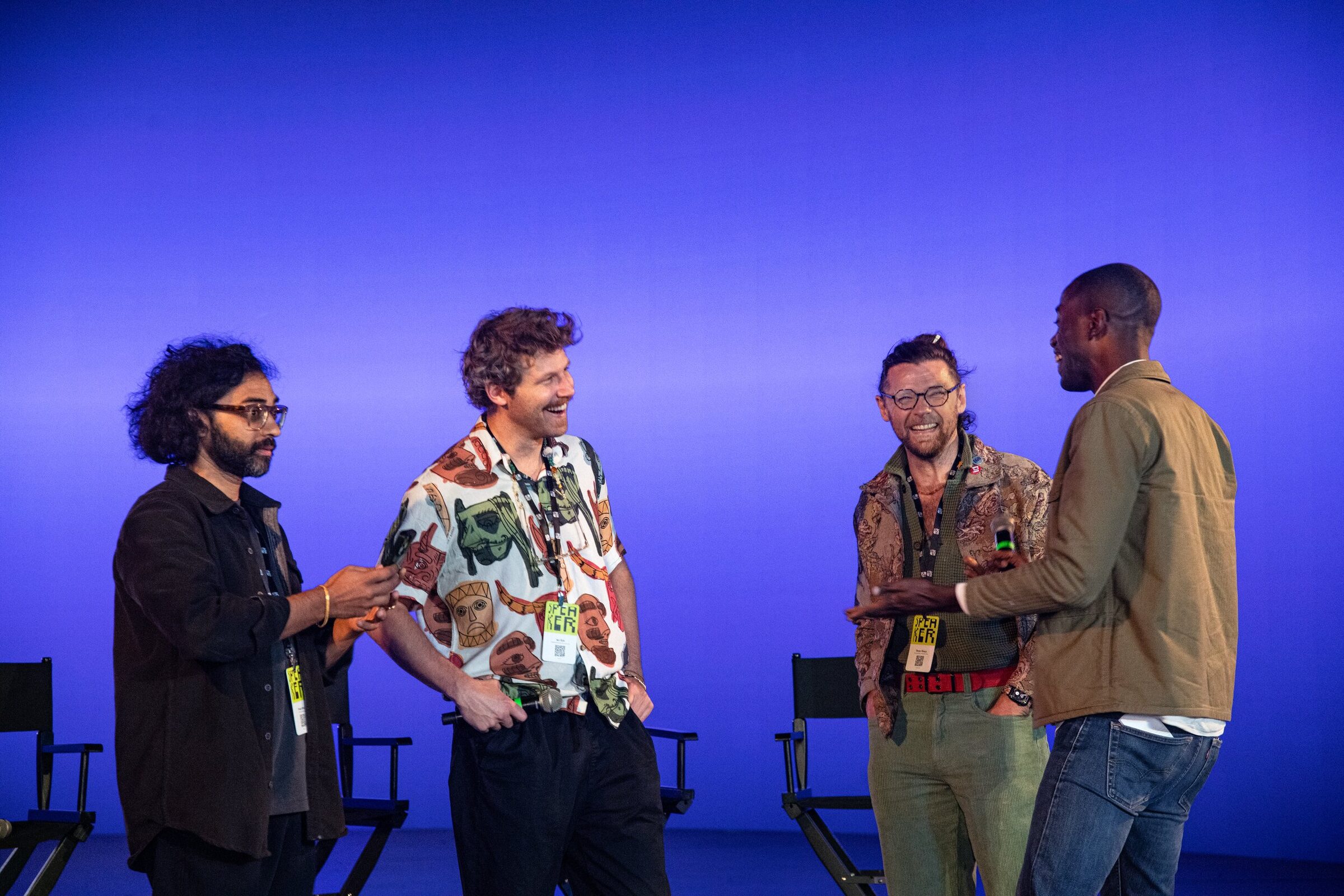 Parag Mital, Ian Eck, Oscar Sharp and Maxwell Kangkolo laugh together in front of the blue stage wall.
