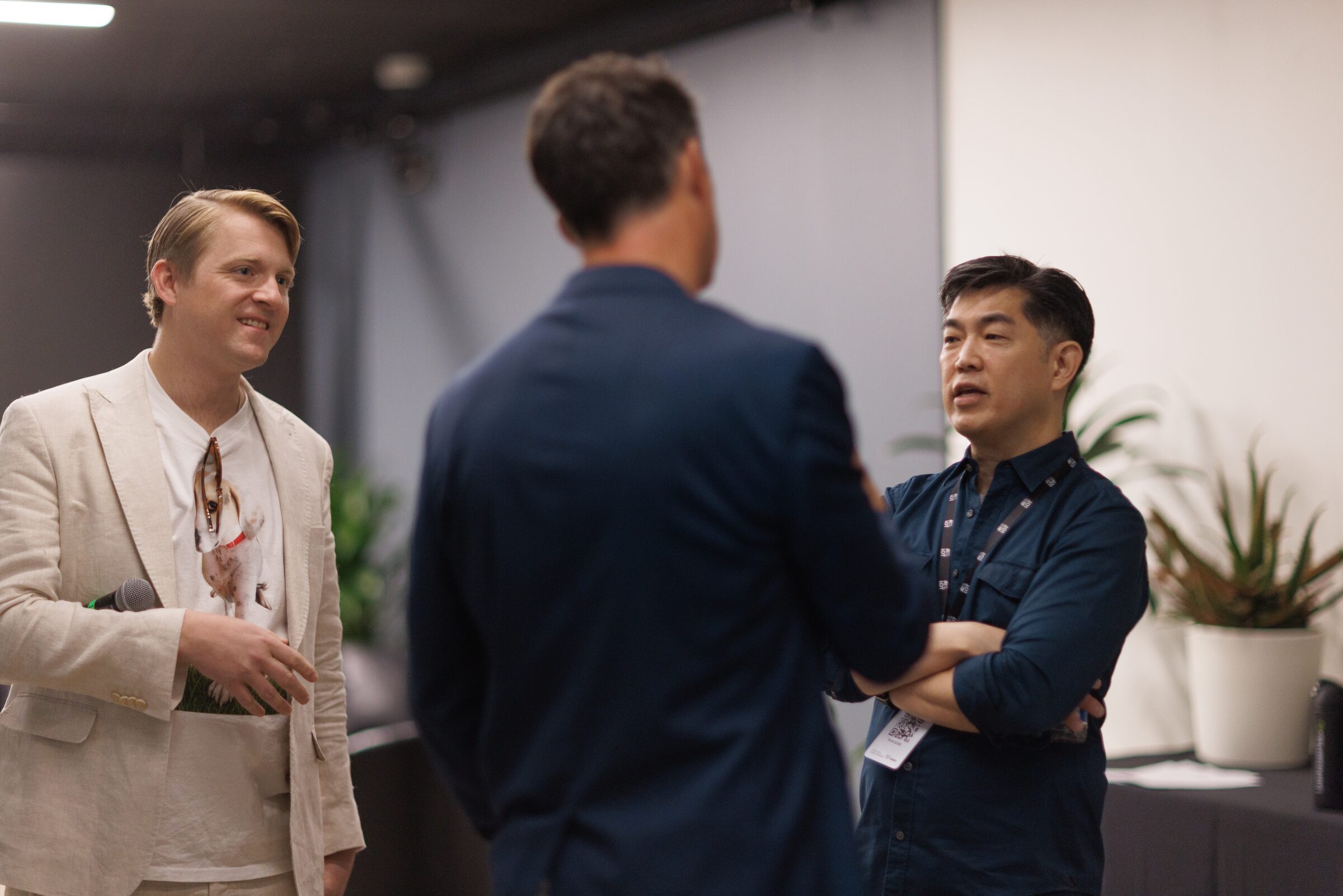Todd Terrazas, Dan O'Brien and Albert Cheng chat, arms crossed and smiling, in a bright green room.